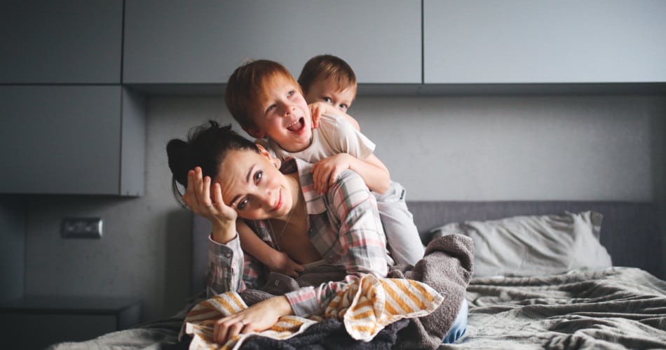 erschöpfte mutter mit zwei kindern auf ihrem rücken