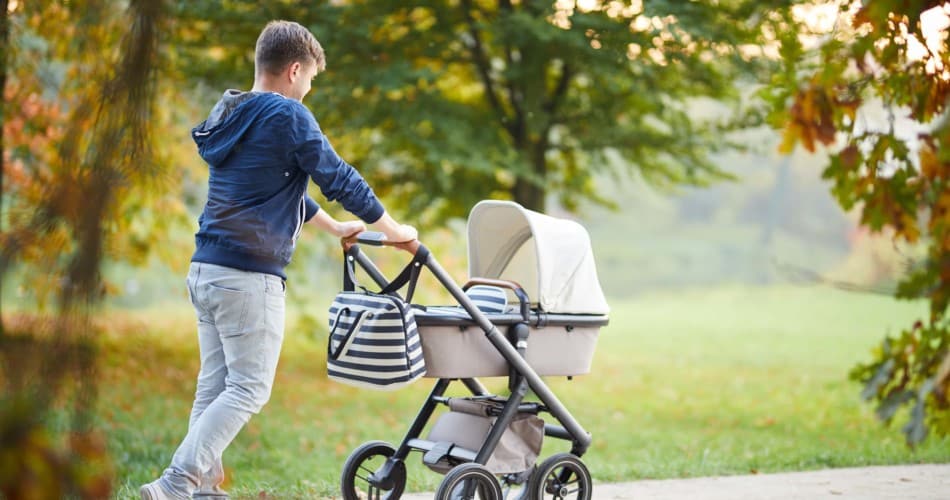 Ein Mann schiebt einen Kinderwagen mit Zubehör.