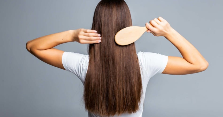 Eine Frau kämmt sich die Haare – Titelbild für Beitrag über Haarausfall nach der Geburt.