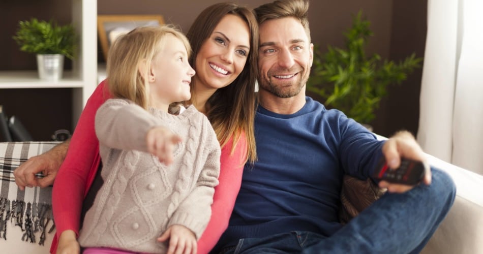 Eine Mutter und ein Vater schauen gemeinsam mit ihrer Tochter Kinderfilme an.