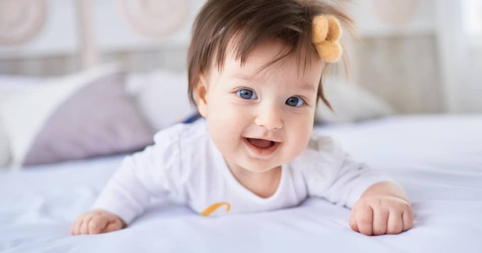 Ein Baby mit langen Haaren liegt im Bett.