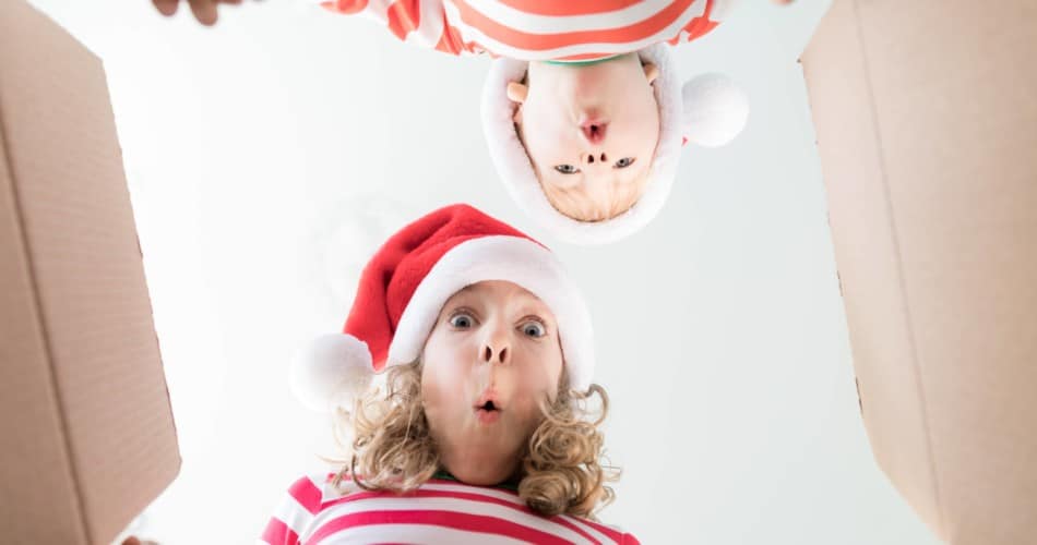 Kinder schauen in ein offenes Paket und sind überrascht.