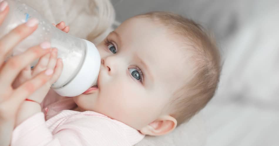 Ein Baby trinkt nach dem Abstillen aus einer Flasche.
