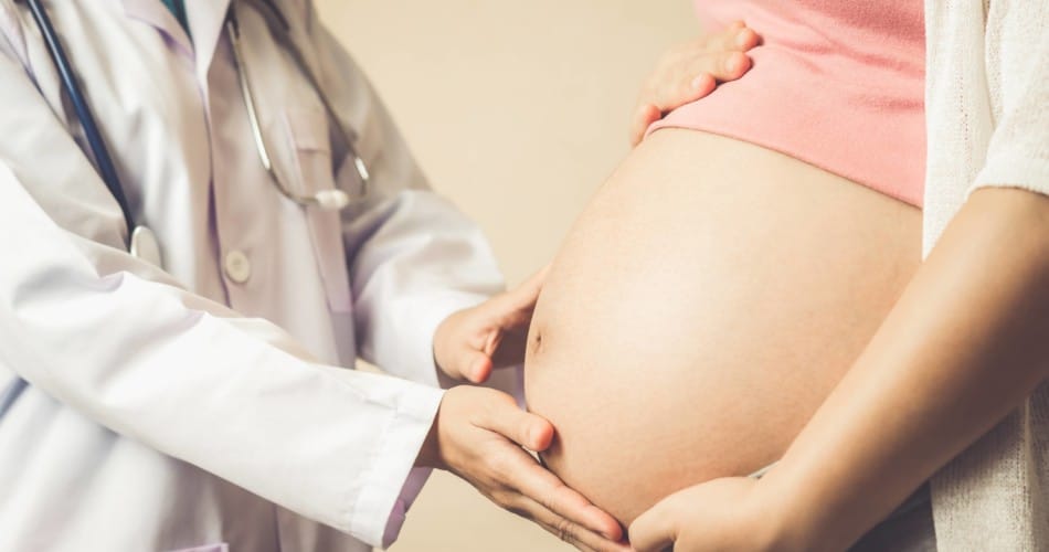 Arzt fast den Bauch einer schwangeren Frau an.