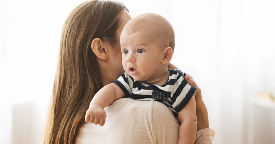 Eine Mutter hält ihr Baby in der Schulterhaltung.