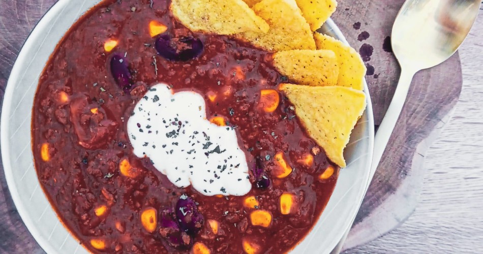 Chili sin Carne serviert mit veganer Creme fraiche und Tortillachips.