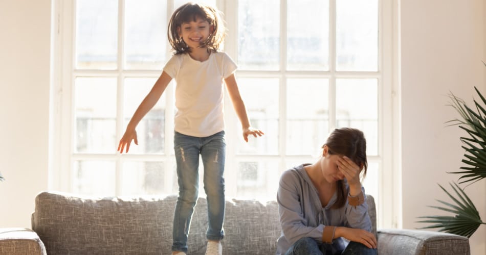Ständig überdrehtes Kind springt auf der Couch neben seiner Mutter