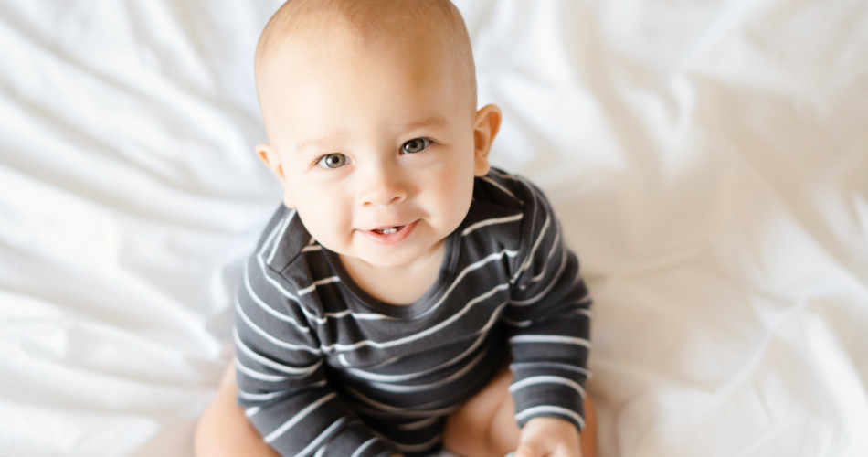 6 Monate altes Baby sitzt im Bett