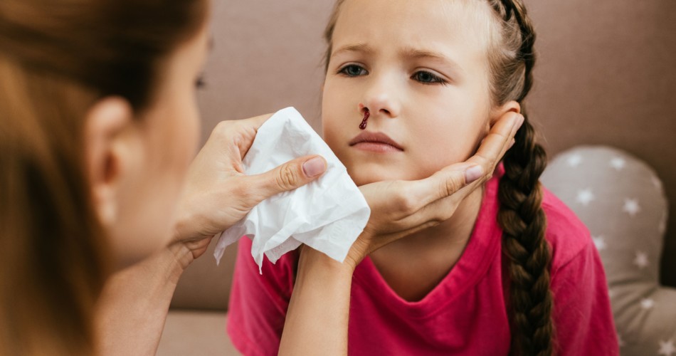 Eine Mutter kümmert sich um die blutende Nase ihrer Tochter