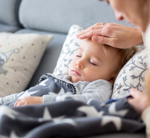 Eine Mutter überprüft per Hand, ob ihr Baby bzw. Kleinkind, das mit dem RS-Virus infiziert ist, Fieber hat.