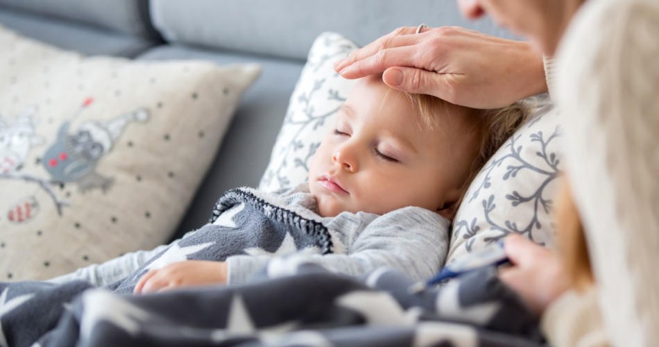 Eine Mutter überprüft per Hand, ob ihr Baby bzw. Kleinkind, das mit dem RS-Virus infiziert ist, Fieber hat.