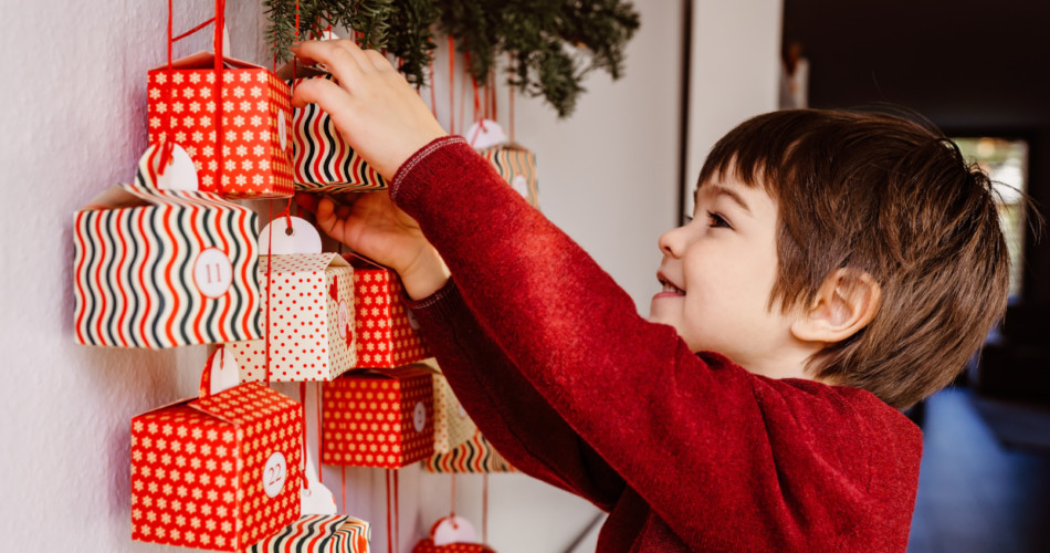 Kind packt Adventskalender aus
