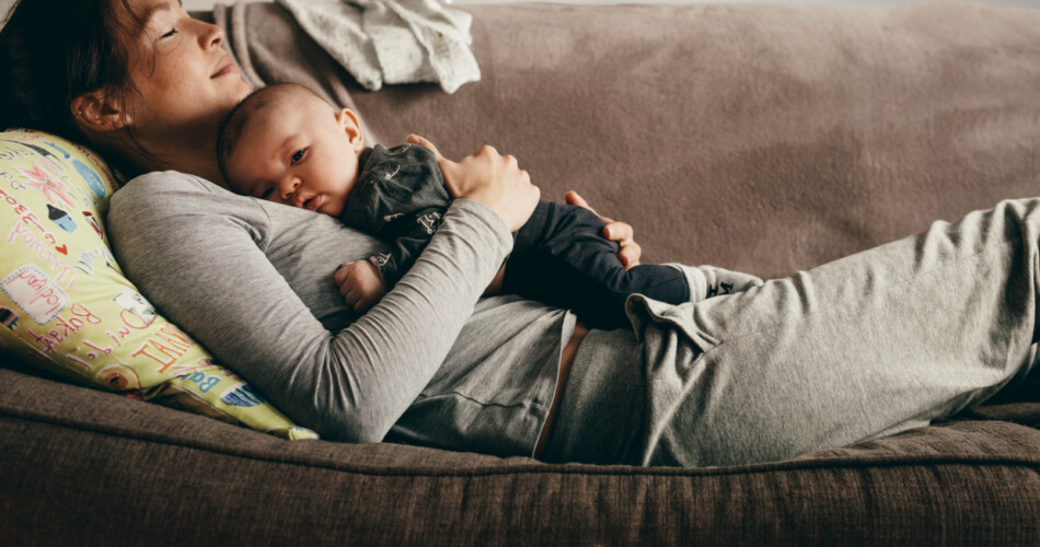 Mutter mit Baby auf dem Sofa schläft.