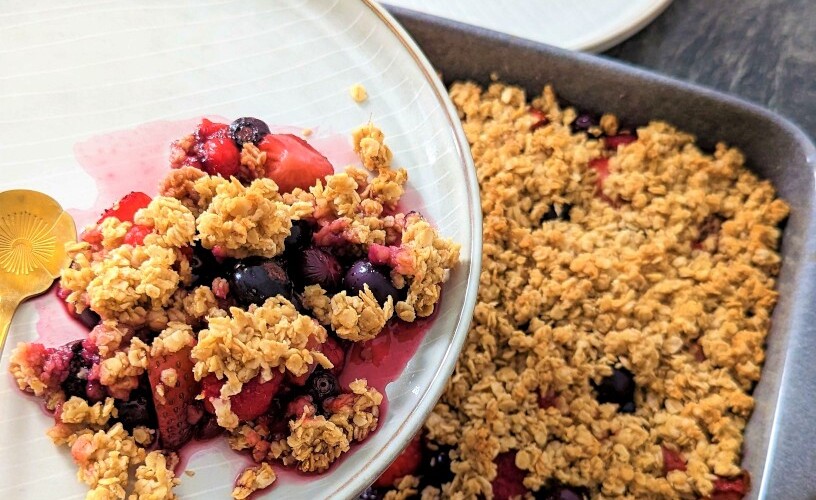 Beeren-Crumble serviert auf einem Teller und gebacken in einer Auflaufform