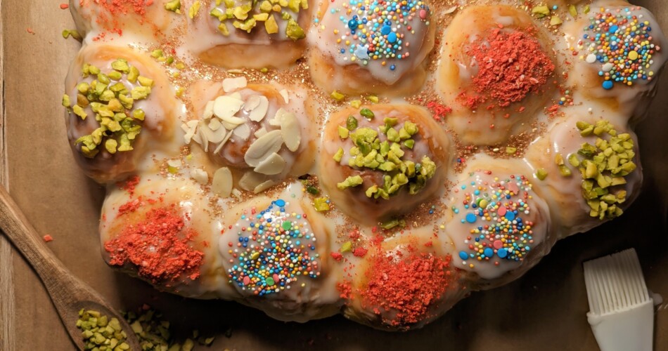 Buchteln mit verschiedenen Toppings in Osterei-Form liegen frisch gebacken auf einem Tisch