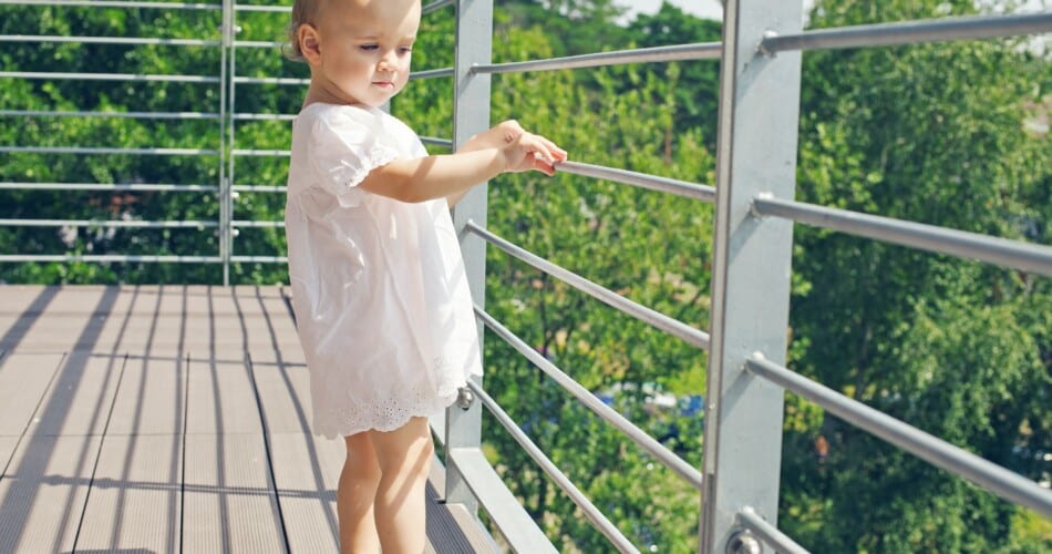Ein kleines Kind auf einem nicht kindersicheren Balkon