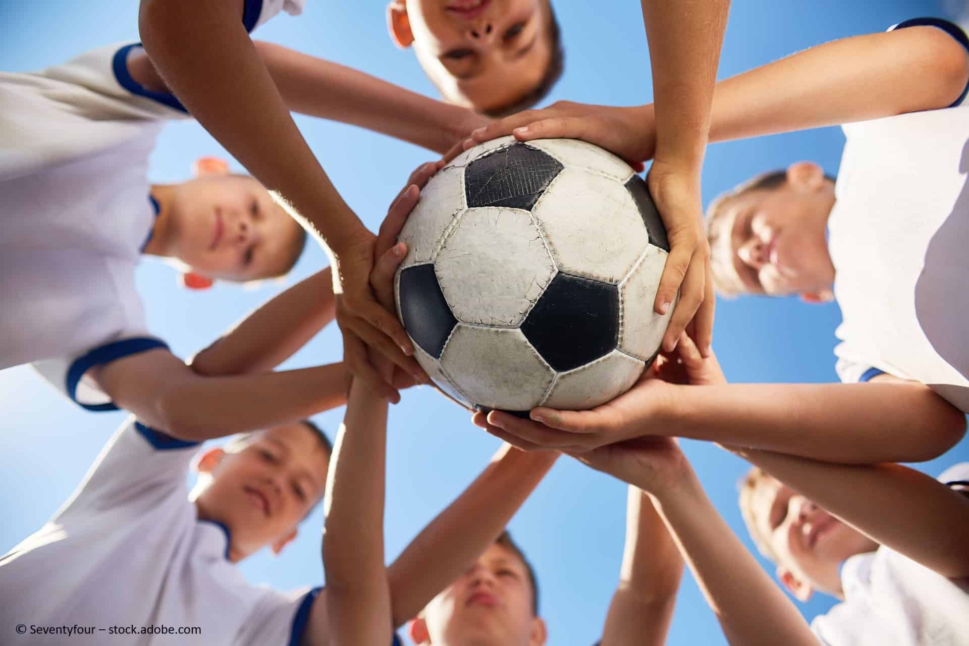 Kinder halten einen Fußball.