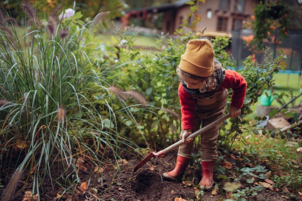 Gärtnern mit Kindern im Februar: Kind kümmert sich um den Gemüsegarten und gräbt die Erde um.