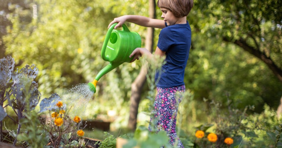 Kind gießt Pflanzen mit Gießkanne beim Gärtnern mit Kindern im April