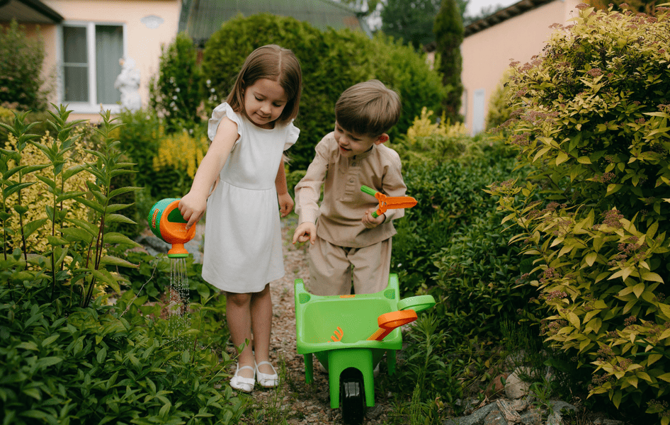 Kinder spielen mit einer Schubkarre im Familiengarten