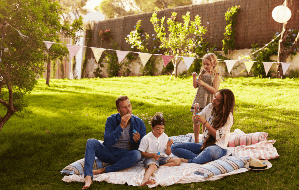 Familie macht eine Pause im Garten und spielt gemeinsam mit Seifenblasen