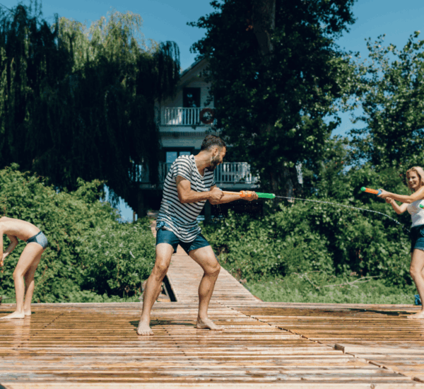 Familie kühlt sich mit Wasser an einem heißen Sommertag im Garten ab.