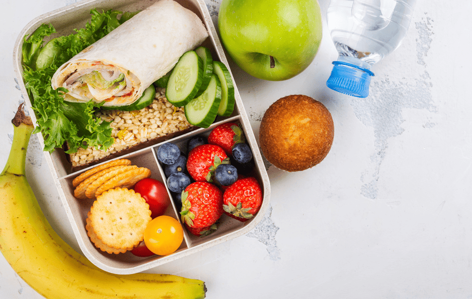 Eine farbenfrohe, gesunde Snachdose mit frischem Obst, Gemüse und Vollkornbrot für den Sommerausflug.